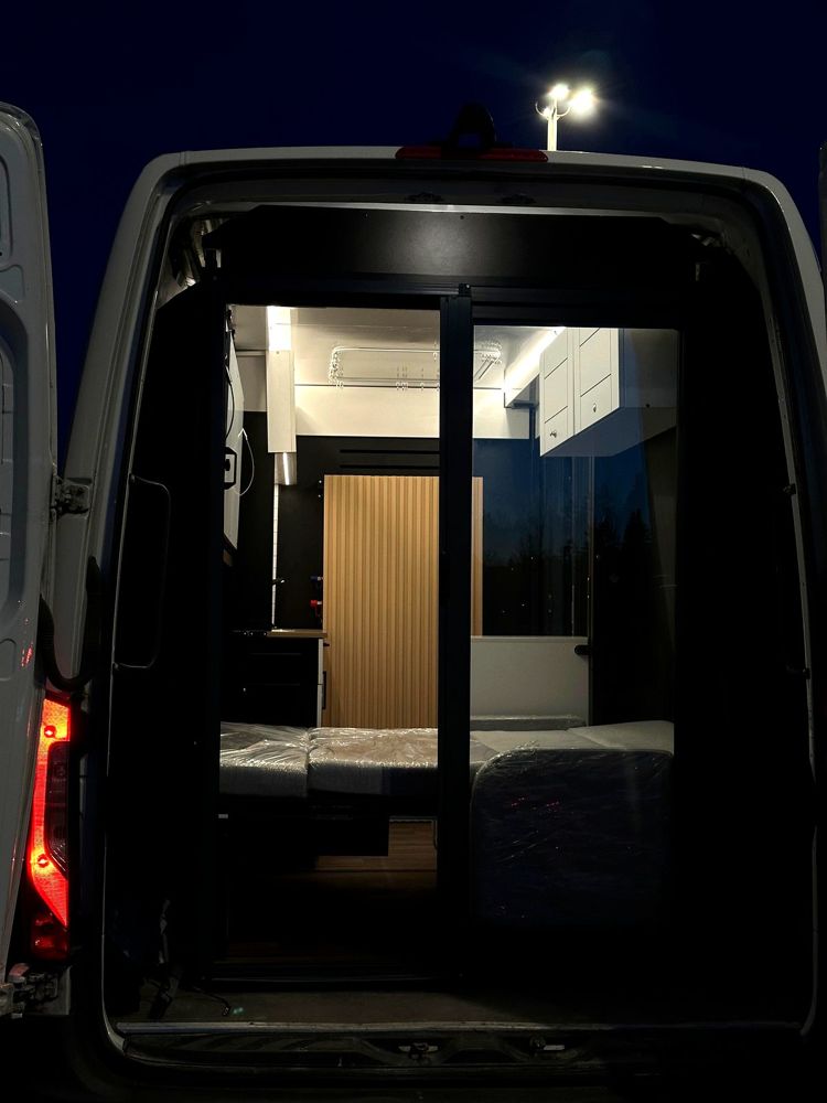 Unité d'hébergement installée dans une van, éclairée de l'intérieur la nuit